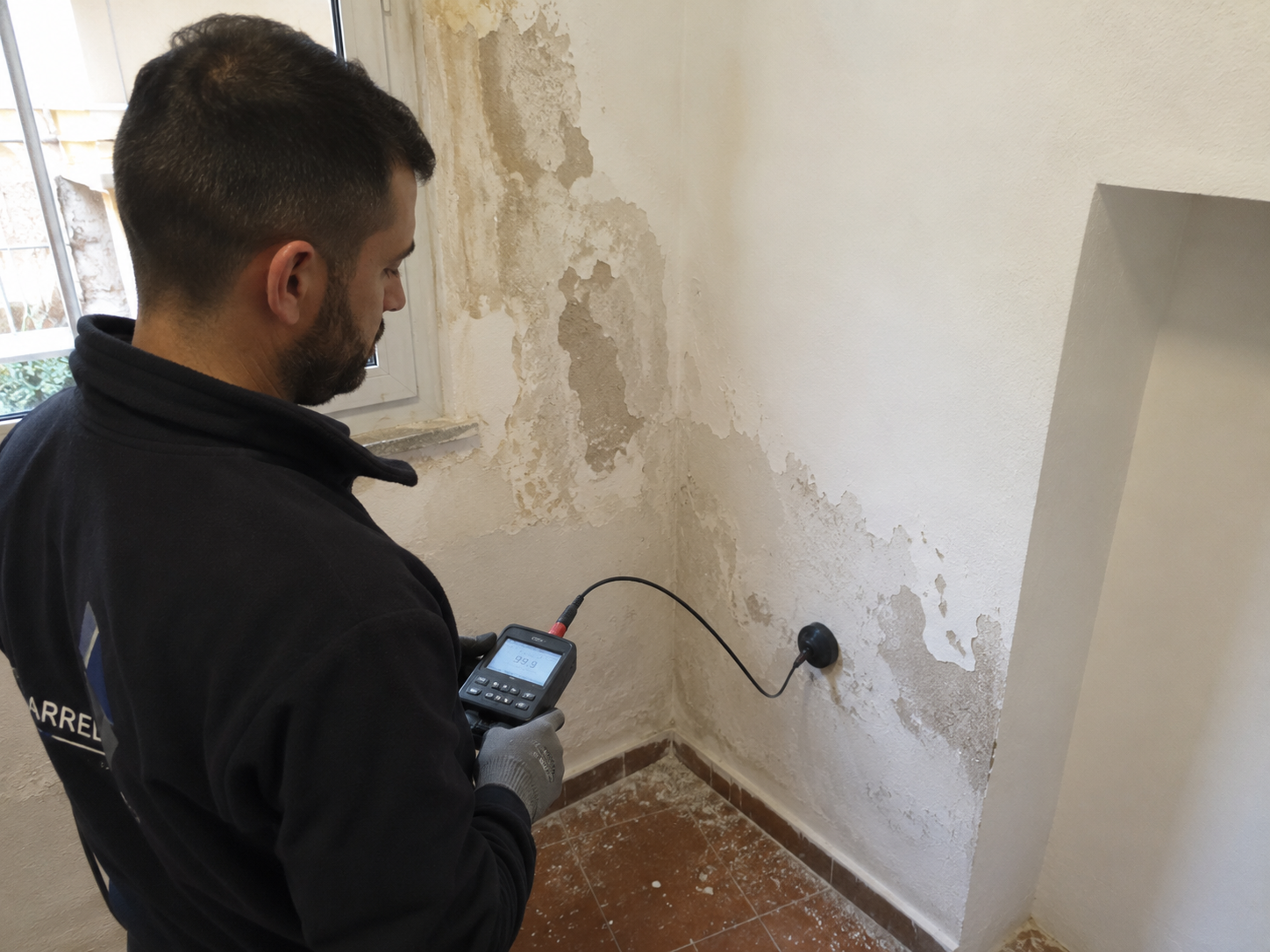 Tècnic mesurant el nivell d'humitat d'un mur durant un diagnòstic a Barcelona
